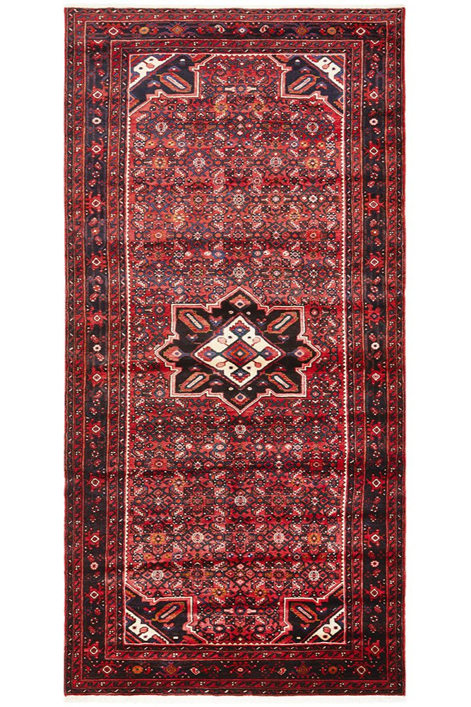A hand knotted pure wool Hossein Abad rug featuring a geometric herati pattern with rich red, blue, cream, and green colors.
