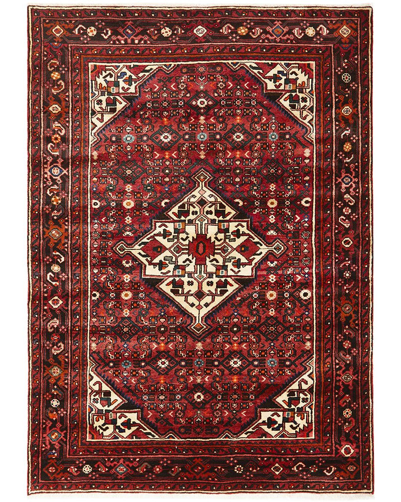 A hand knotted pure wool Hossein Abad rug featuring a geometric herati pattern with rich red, blue, cream, and green colors.