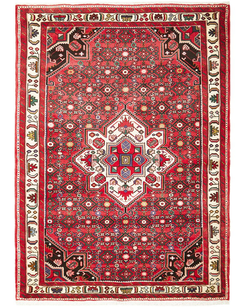 A traditional Hosseinabad rug with a geometric herati pattern, featuring rich red, blue, cream, and green colors on a cotton base.