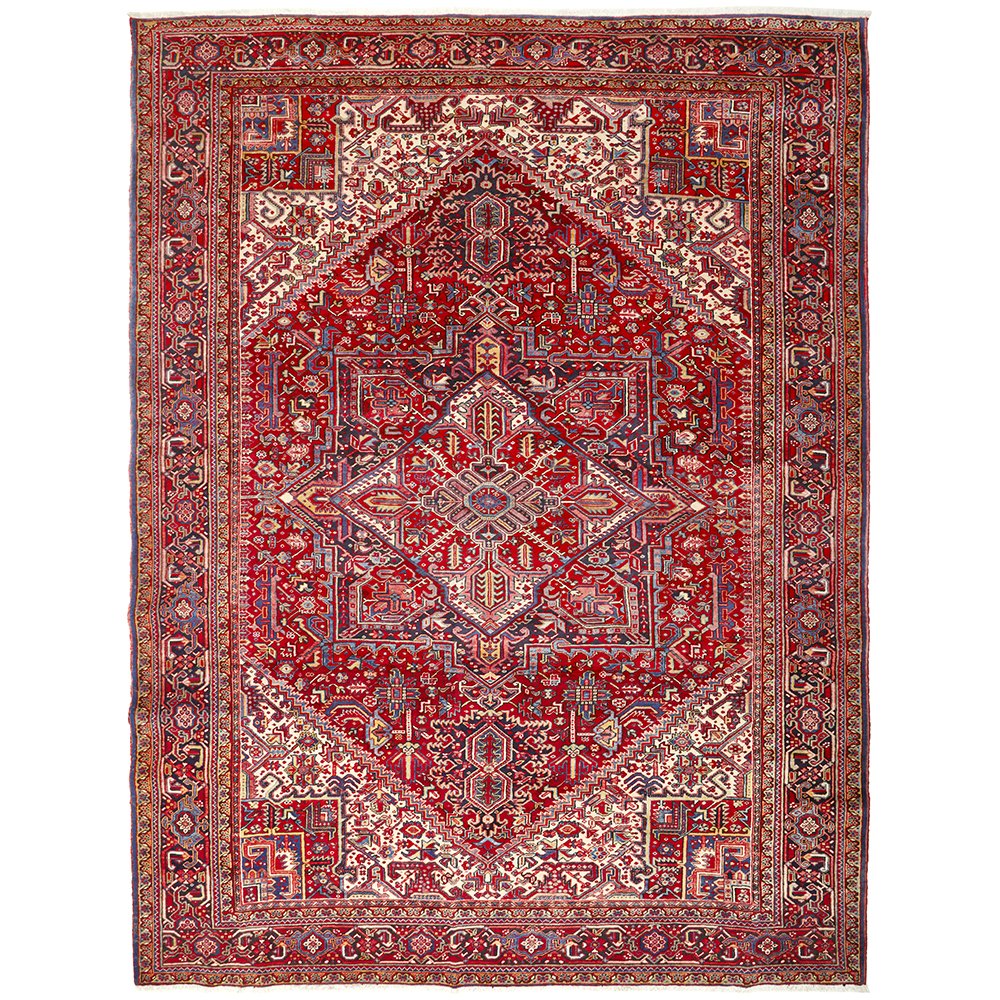 A large, hand knotted Persian rug with a red background and geometric patterns, featuring a central medallion and varied color tones.