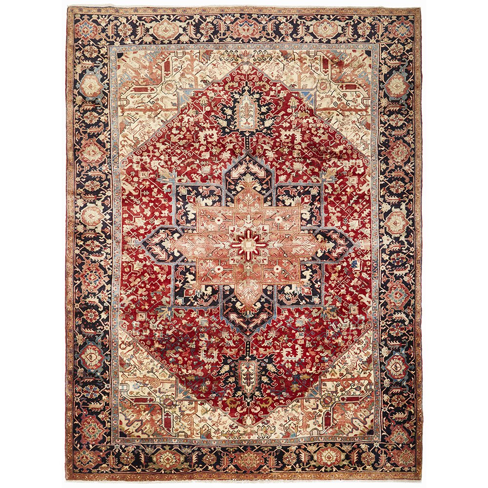 A large, hand knotted Persian rug with a geometric medallion design in the center, featuring red, blue, beige, and ivory colors.