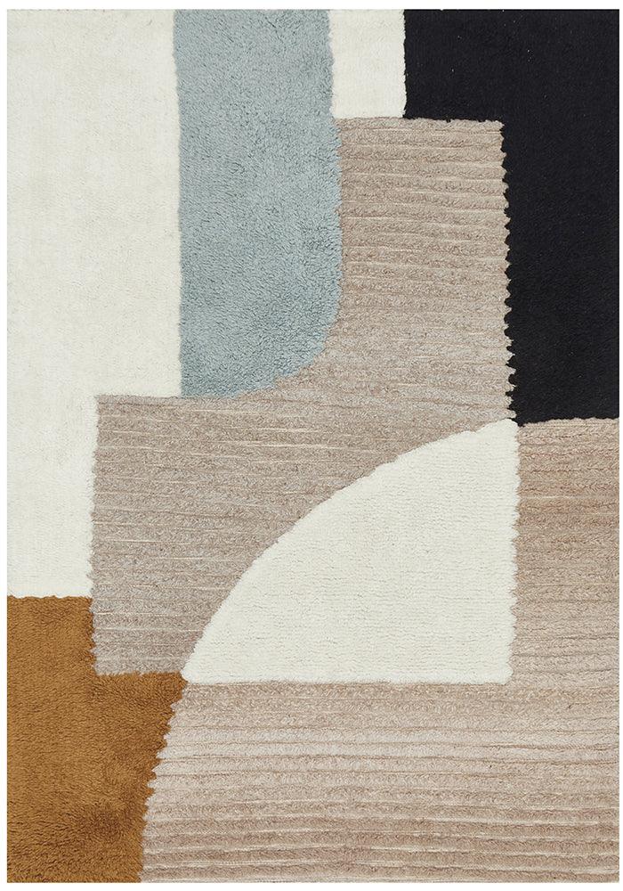 A rectangular rug with a modern geometric pattern in a multicolor palette, featuring blocks of black, blue, beige, and other colors.